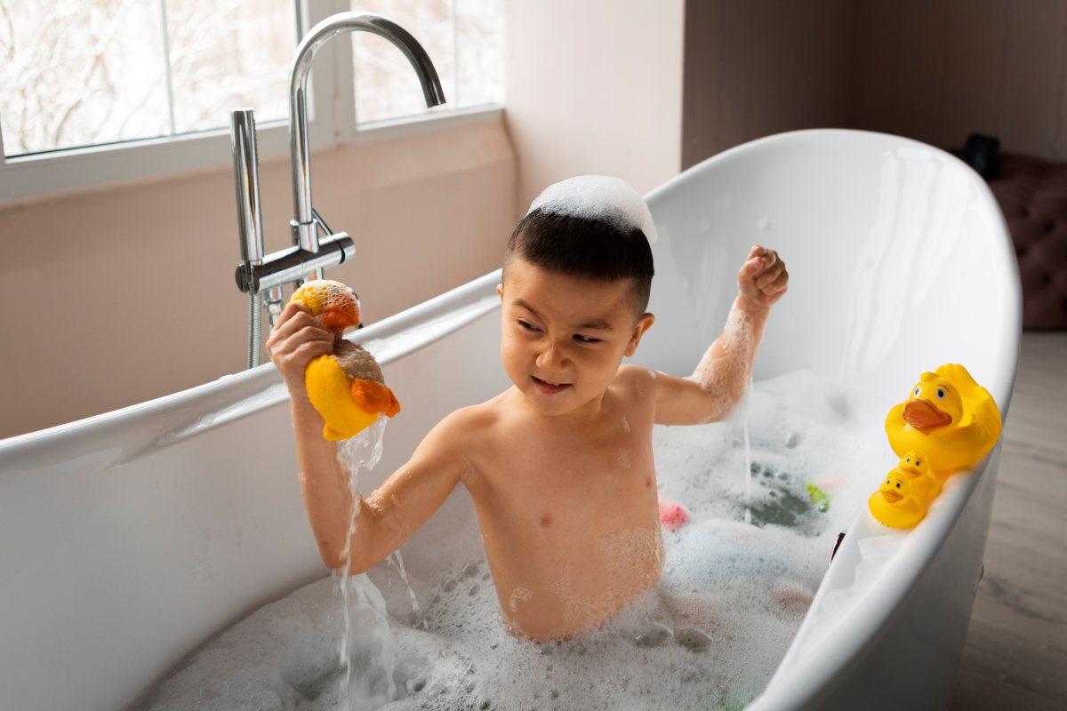 เด็กชายกำลังเล่นของเล่นในอ่างอาบน้ำที่เต็มไปด้วยฟองสบู่อย่างสนุกสนาน